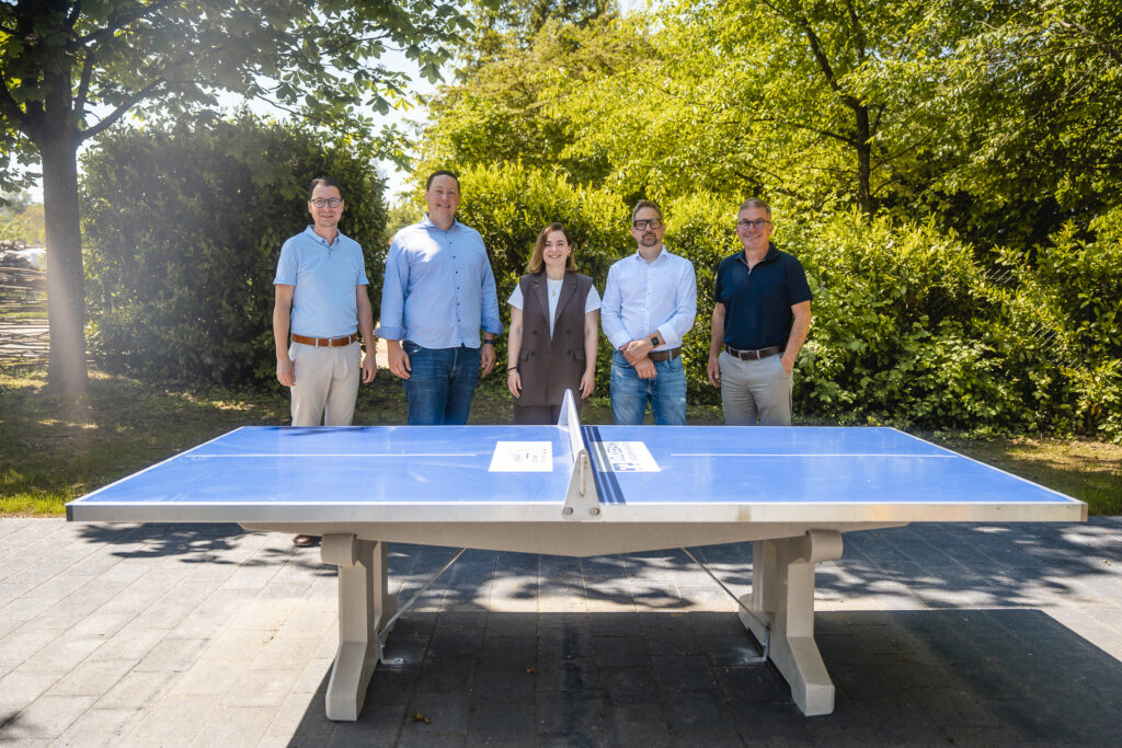 Mehrere Personen stehen hinter einer Tischtennisplatte
